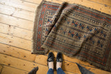 Antique Belouch runner showcasing worn geometric patterns, tattered ends, and rich indigo, camel, black cherry tones.