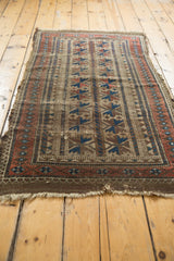 Tattered end of antique Belouch rug, showcasing distressed indigo blue and black cherry red motifs.