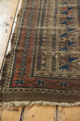 Corner of Antique Belouch runner, showing time-softened geometric patterns and worn fringe.