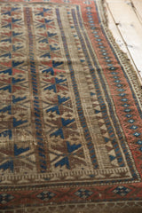 Intricate geometric patterns and border detail in camel, indigo, and red on an antique Belouch.