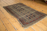 Antique Belouch runner corner, showing tattered fringe and geometric indigo red patterns.