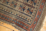 Worn corner of antique Belouch rug, displaying geometric patterns in camel, indigo, and red.