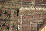 Antique Belouch rug runner's fringed end, deep indigo, red, camel geometric motifs, visible tatter.