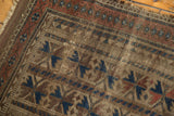 Worn texture of antique Belouch runner, showing geometric indigo, red, and camel motifs.