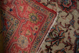 Distressed vintage Meshed rug fold, revealing worn red pile, ivory ground, and edge tatter.