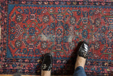 Close-up of vintage Persian Lilihan rug: cherry red and indigo blue pattern with visible foundation and foot.