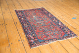 Cherry red and indigo formal patterns on a vintage Lilihan rug, showing visible wear.