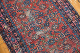 Repeating formal design on vintage Lilihan rug in cherry red, indigo, and wear.