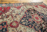 Hand-knotted detail of antique Farahan Sarouk rug showing raspberry red vines and indigo floral elements.