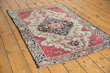 Corner of antique Farahan Sarouk rug, showing raspberry red floral border, indigo vines.