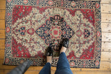 Antique Farahan Sarouk rug: contrasting raspberry red medallion and indigo floral patterns on ivory.