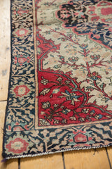 Elaborate indigo border and antique ivory floral motifs on an antique Farahan Sarouk rug corner.