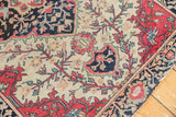 Antique Farahan Sarouk rug corner showing intricate floral vines, crimson border, and ivory field.