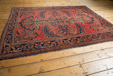 Vintage Lilihan rug's vibrant cherry red field, dancing floral vinery, and deep indigo border.