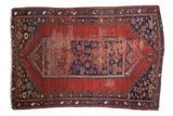 Antique Caucasian rug with cherry red field, indigo medallion, and playful geometric floral motifs.