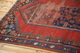 Antique Caucasian rug section, cherry red field with low pile and detailed indigo geometric border.