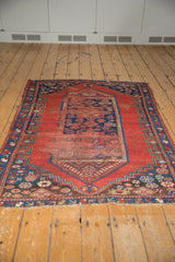 Tattered fringe and worn cherry red field of the Antique Caucasian rug's lower corner.