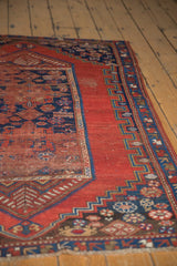 Geometric indigo blue border and varied stylized motifs of an antique Caucasian rug.