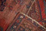 Textured cherry red pile, indigo geometric border, and time-softened fringe, antique Caucasian rug.