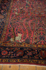 Kashan antique rug: pictorial leopard and tree of life motif on a raspberry red field.
