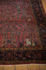 Antique Kashan rug: spotted leopard, raspberry tree-of-life field, intricate navy blue floral border.