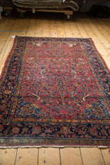 Kashan rug detail: dark raspberry red field with birds, indigo border, and fringe.
