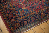 Antique Kashan rug corner showcasing indigo blue floral border, dusty gold accents, and aged fringe.