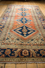 Vintage Hamadan rug's navy and terracotta border, ivory Herati field, and fringe.