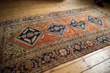 Vintage Hamadan rug corner with navy blue medallion, serrated fish motifs, and madder root red field.
