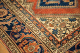 Vintage Hamadan rug corner displaying terracotta, navy, ivory Herati with serrated details.