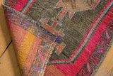 Distressed vintage Oushak rug corner reveals hand-knotted texture, geometric motif, fuchsia, and abrash.