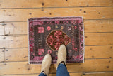 Distressed Oushak rug with faded charcoal field, pink border, and weaver inscriptions.