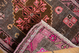Folded corner of the distressed Oushak rug, highlighting secured fuchsia and charcoal village weave.