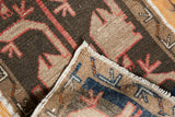 Vintage Oushak rug folded corner, showing playful village weave, tight edge, charcoal, beige, red, and blue.