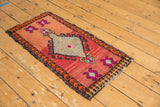 Upper corner detail of a distressed vintage Oushak rug showing playful red, fuchsia, and orange motifs.