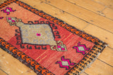 Distressed vintage Oushak rug with playful tan and fuchsia asymmetric village motif on a red field.