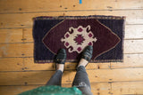 Distressed Turkish Oushak rug featuring a bold ivory and eggplant geometric motif.
