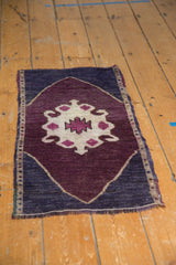 Distressed Oushak rug corner with eggplant field, dark navy border, and visible even wear.