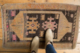 Playful geometric motifs in charcoal, bright pink, and pale orange on a distressed Oushak rug.