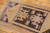 Playful asymmetric village weave on a distressed Oushak rug with charcoal, tangerine, and pink tones.