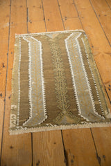 Hand-woven Jijim rug detail with distressed texture, coffee brown, olive, and ivory plant motif.