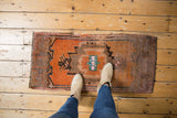 Distressed tangerine orange Oushak rug with brown and denim blue geometric pattern.