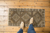 Distressed texture of vintage Jijim rug mat runner with geometric medallions and earthy colors.