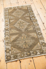 Distressed Jijim rug close-up, showing geometric diamond patterns in brown and ivory.