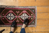 Distressed vintage Oushak rug detail: diamond medallion, sky blue, hot pink, and narrow border.