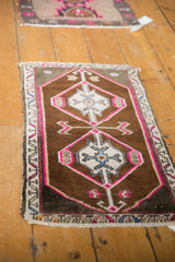 Hot pink outlined diamond medallion with ram's horn finials on a distressed Oushak rug.