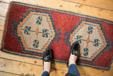 Distressed vintage Oushak rug corner, cherry red field, beige geometric medallion with blue blossoms.
