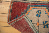 Folded vintage Oushak rug corner revealing worn cherry red pile and original side cord selvages.