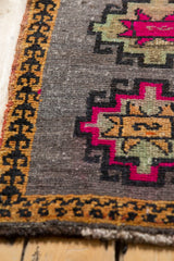 Distressed Oushak rug corner, showing saffron germinating plant motif border and hot pink design.
