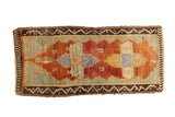 Distressed Oushak rug mat with copper orange and pale celadon quatrefoil medallion, brown borders.
